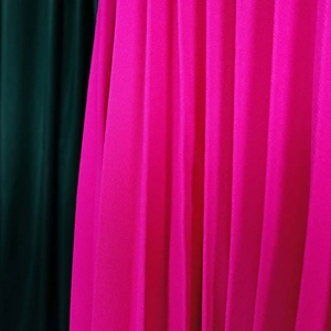 Detail shot of rose red pleated fabric with fine vertical texture and twill weaving pattern