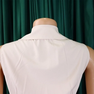 Detail view of the back of a beige V-neck jumpsuit with a minimalist pleated design