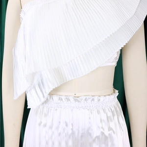 Detailed view of the elegant ruffled one-shoulder top and pleated white fabric texture
