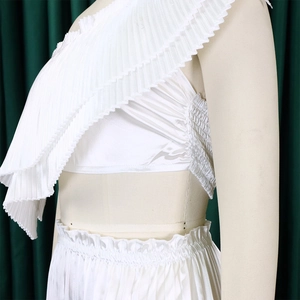 Detail of white two-piece set featuring pleated fabric and one-shoulder ruffle top design