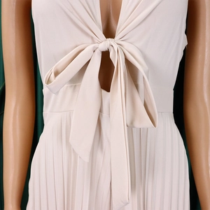 Detail of beige V-neck pleated jumpsuit featuring a chic front bow-tie and refined pleats