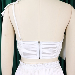 Close-up of white satin backless top with metal zipper and pleated elastic detail