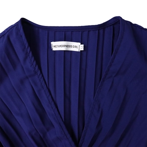 Gros plan sur la robe bleue à col en V avec plissage vertical délicat et étiquette intérieure