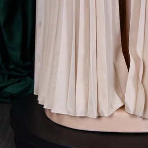 Detailed close-up of beige pleated fabric with elegant texture and fluid drape
