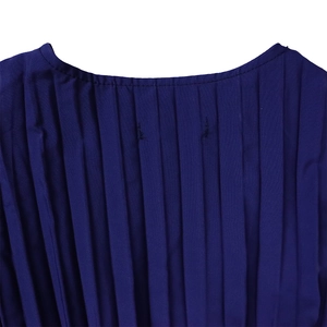 Détail de la texture du tissu plissé bleu foncé et de l'encolure de la robe longue