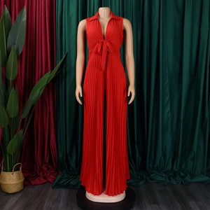 Detail of red sleeveless pleated jumpsuit with shirt collar and waist tie bow decoration
