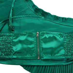 Detailed close-up of emerald satin fabric with zipper closure and fine pleated texture
