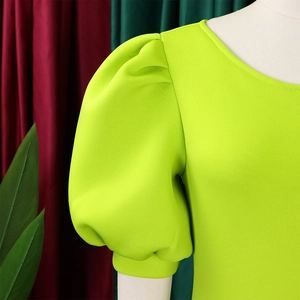 Close-up of vibrant neon green dress featuring elegant puff sleeves and a round neckline