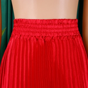 Detailed view of elastic waistband and pleated texture on this red satin maxi skirt