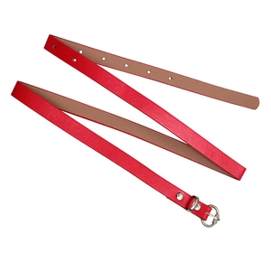 Detailed view of a slim bright red leather belt with a silver pin buckle and belt loop