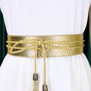 Detailed view of a gold snakeskin embossed belt with woven rope and fringe tassels