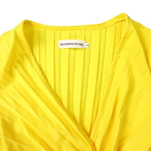 Gros plan d'une robe jaune vif avec décolleté en V croisé et détails plissés fins