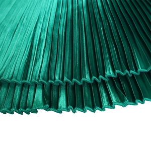 Detailed close-up of pleated emerald green fabric with glossy metallic satin texture