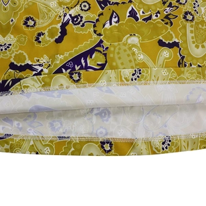 Macro detail of ethnic paisley print on yellow fabric with double-needle hem stitching
