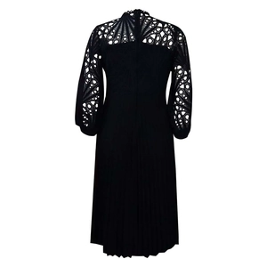 Detail view of lace hollowed-out back and pleated hem on a black long-sleeved dress