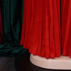 Close-up detail of red pleated fabric with elegant draping texture on wide-leg jumpsuit