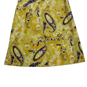 Close-up of vibrant yellow jumpsuit fabric featuring a detailed green paisley floral print