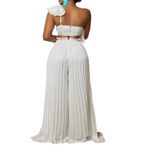 Detail of white one-shoulder ruffle crop top and high-waisted pleated wide-leg trousers