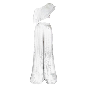 Detail of white one-shoulder ruffled crop top and pleated wide-leg pants on white background