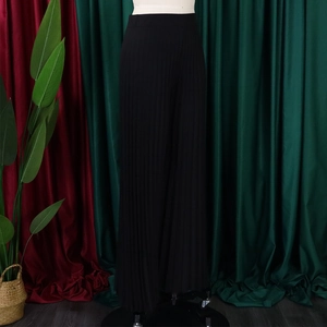 Detail of high waisted pleated wide leg trousers in black with a flowing silhouette