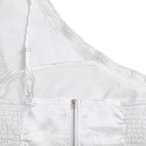 Detail of white two-piece set featuring pleated fabric, satin lining, and silver zipper