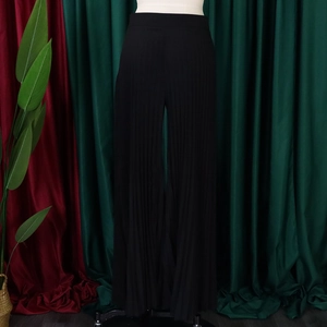 Detail of high waisted pleated wide leg trousers in black fabric with vertical textures