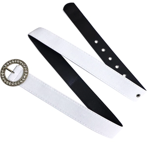 Détail d'une ceinture en daim blanc avec boucle circulaire argentée ornée de strass