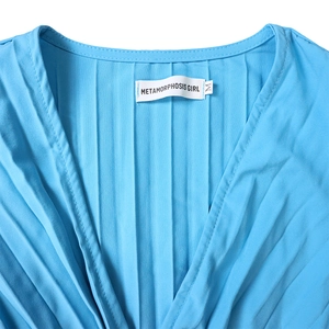 Détail de la robe bleu ciel à col en V avec plis élégants et étiquette de taille tissée