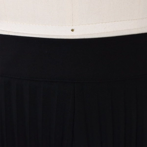 Macro detail of high waist pleated trousers featuring precise stitching and texture
