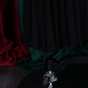 Detail of high-waisted pleated trousers showing the fine vertical texture and hemline