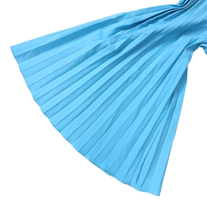 Détail du tissu plissé bleu clair montrant la texture fine et la couture de l'ourlet
