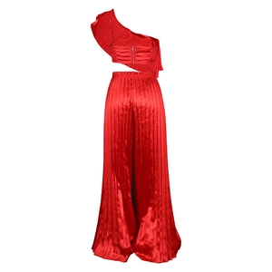 Detail of red satin pleated set showing one-shoulder ruffle top and wide leg pants