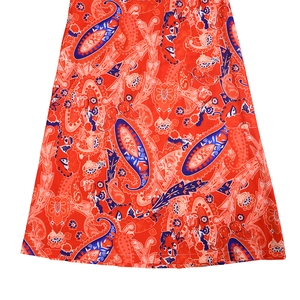 Close-up of vibrant orange paisley print fabric on bohemian jumpsuit hemline