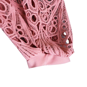 Close-up of intricate lace hollow-out floral patterns and wavy edges on a pink dress