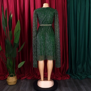 Macro detail of dark green shimmer dress featuring a cape sleeve design and gold belt