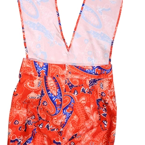 Detail of bohemian orange paisley print jumpsuit featuring a concealed zipper and deep V neck