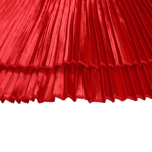 Close-up of red pleated satin fabric detail with elegant ruffled hem and vertical folds