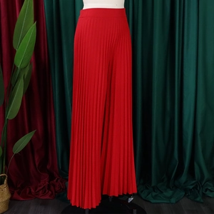 Close-up of high-waist red pleated wide-leg trousers with elegant vertical drape texture