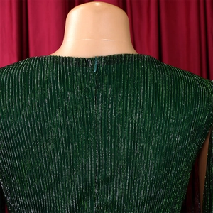 Detail of dark green metallic pleated dress showing the concealed back zipper and texture