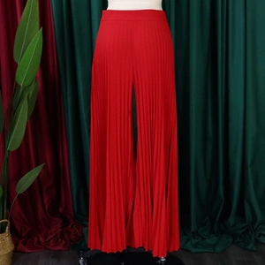 Detailed view of red pleated wide leg trousers featuring a high-waisted design and fluid drape