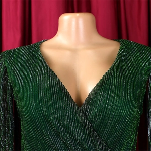 Detail of green pleated metallic fabric with V-neckline and elegant waist design