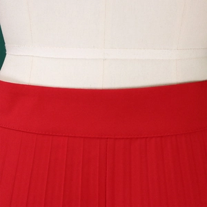 Detail view of high waist red pleated wide leg trousers with premium vertical pleats