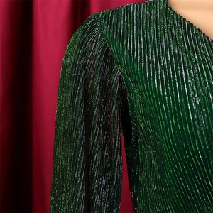 Close-up of metallic pleated fabric in dark green showing luxury texture and V-neck seam
