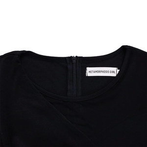 Detail view of round neckline with invisible back zipper and brand label on black dress