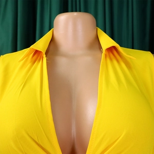 Detail of a bright yellow pleated jumpsuit featuring a deep V-neck and lapel design