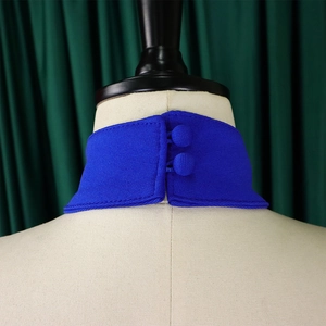 Detail of royal blue stand collar with fabric-covered buttons and fine stitching texture