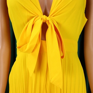 Detail of yellow V-neck pleated jumpsuit featuring a waist tie and micro-pleat fabric
