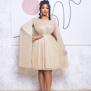 Close-up of champagne pleated V-neck dress featuring elegant cape sleeves and belted waist