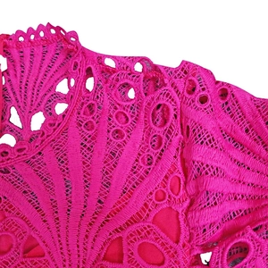 Detail of rose red lace fabric with intricate hollow-out floral patterns and scalloped edges