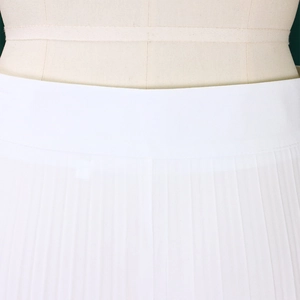 Detailed close-up of high-waisted pleated wide-leg trousers in elegant white woven fabric